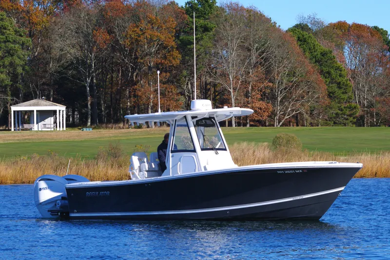 Slide: The Image of 2023 Regulator 28 boat on a calm lake with autumn trees in the background. - 9