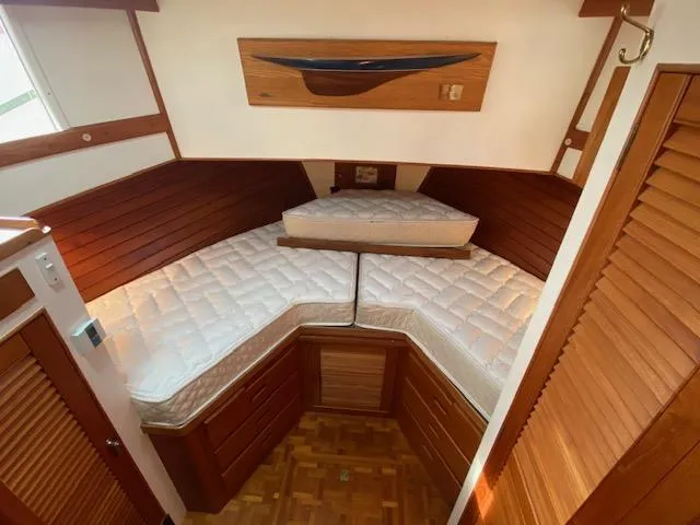 Slide: The Image of 1993 Grand Banks Classic cabin with V-berth, wooden paneling, and storage cabinets. - 16