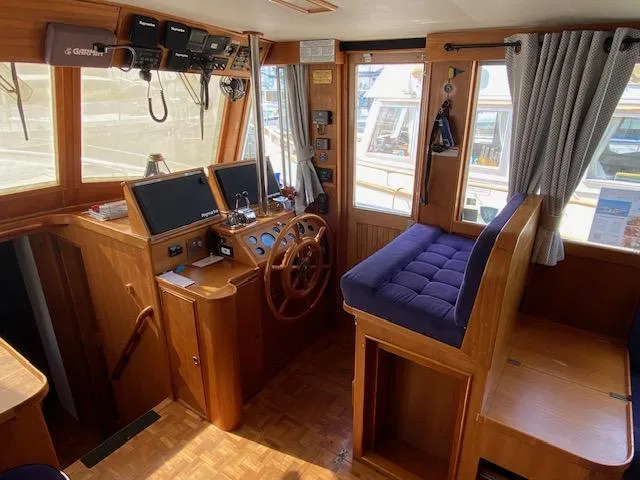 Slide: The Image of 1993 Grand Banks Classic boat interior with wooden helm, navigation equipment, and cushioned seating. - 3