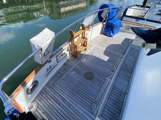 Slide: The Image of 1993 Grand Banks Classic yacht deck with wooden flooring and railing, docked by calm water. - 36