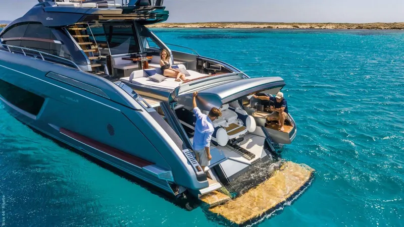 Slide: The Image of 2024 Riva 66' Ribelle yacht cruising near coastal town, scenic backdrop. - 6