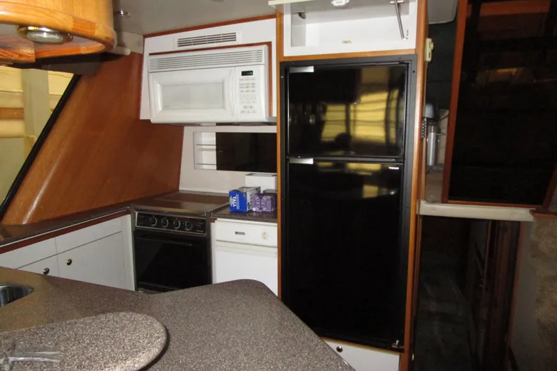 Slide: The Image of 1999 Bayliner 4788 Pilot House Motoryacht kitchen with microwave, stove, and refrigerator. - 19