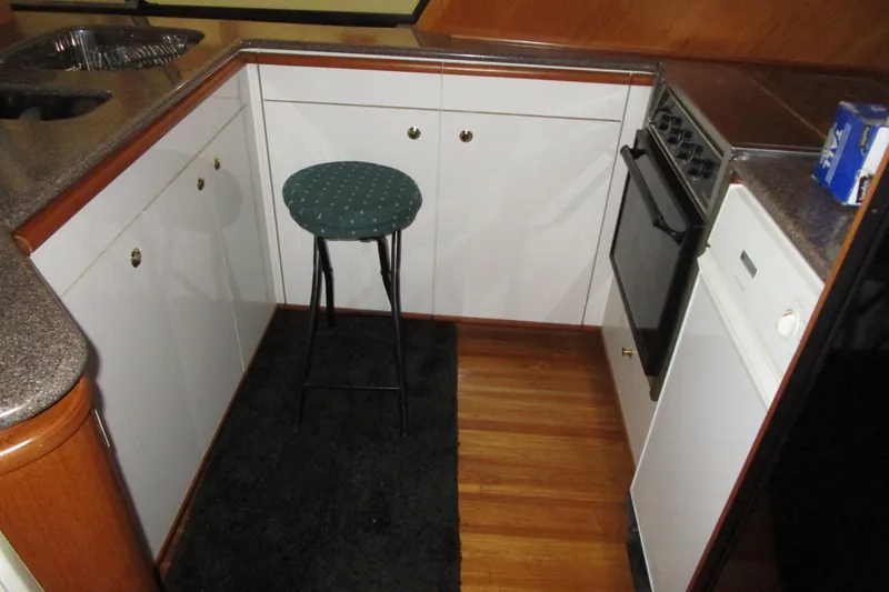 Slide: The Image of 1999 Bayliner 4788 Pilot House Motoryacht kitchen with stool, oven, and dishwasher. - 21