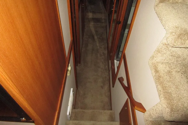 Slide: The Image of Staircase inside 1999 Bayliner 4788 Pilot House Motoryacht, featuring wooden handrails and carpeted steps. - 41