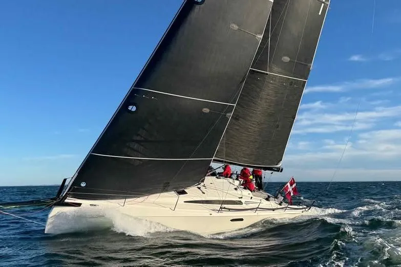 The Image of 2025 X-Yachts XR 41 sailing on open sea with black sails and crew. - 0