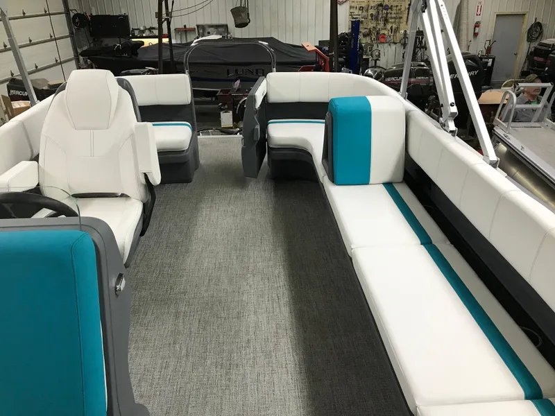 Slide: The Image of 2025 Avalon AURA boat interior with white and teal seating, gray flooring. - 17