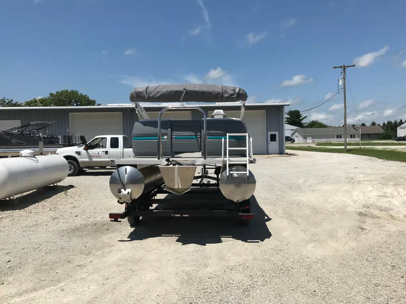 Slide: The Image of 2025 Avalon AURA pontoon boat on trailer, parked outdoors under a clear sky. - 2