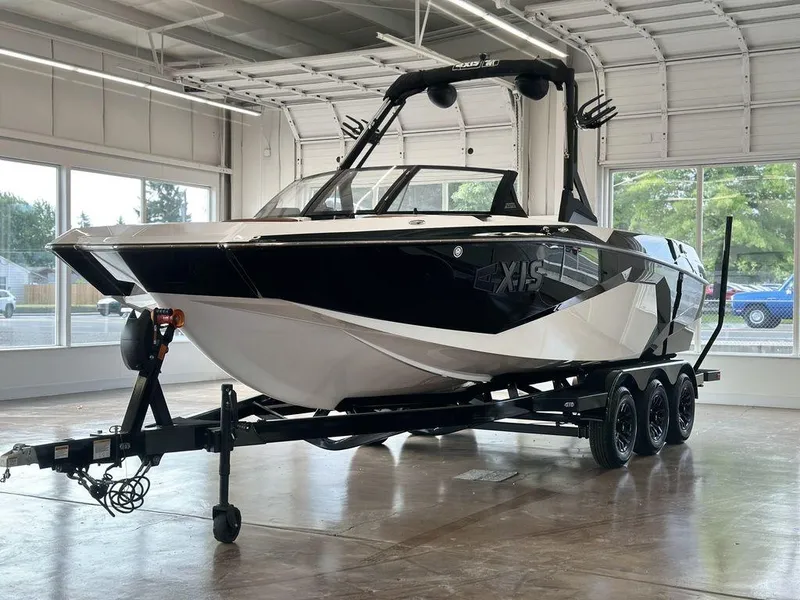 Slide: The Image of 2025 Axis A245 boat on trailer in a showroom, featuring sleek black and white design. - 12