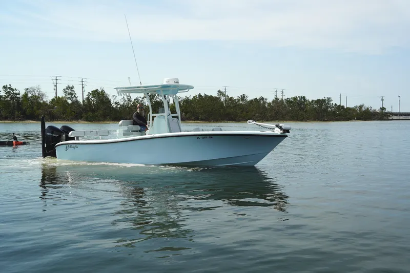 Slide: The Image of 2020 Yellowfin 26 Hybrid boat cruising on calm water near a forested shoreline. - 39