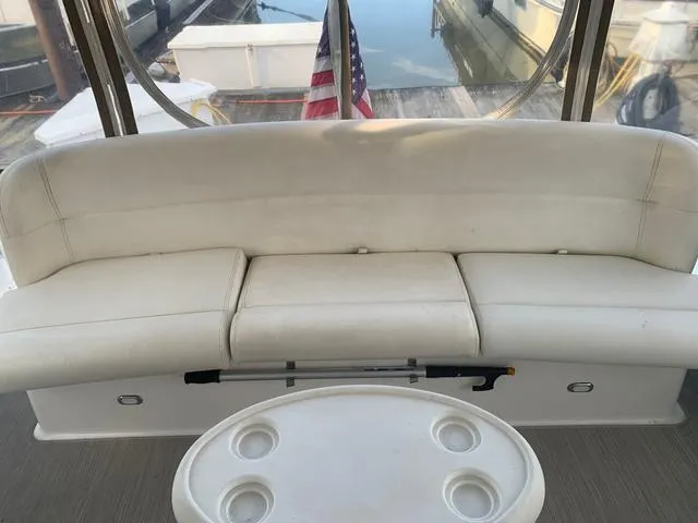 Slide: The Image of 1999 Tiara Yachts 3500 Express interior with white seating and table, docked by water. - 19
