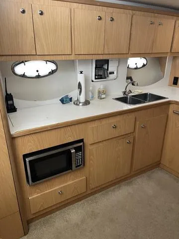Slide: The Image of 1999 Tiara Yachts 3500 Express galley with wood cabinets, microwave, sink, and porthole windows. - 23