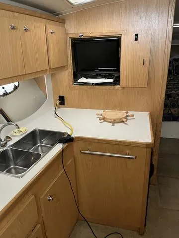 Slide: The Image of Interior of 1999 Tiara Yachts 3500 Express, featuring kitchenette with sink and TV. - 25