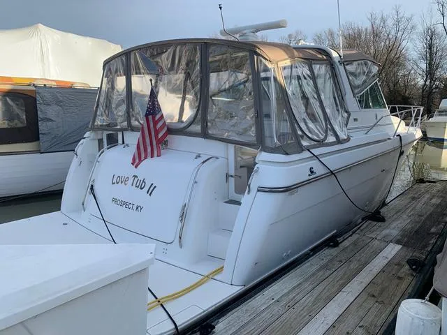 Slide: The Image of 1999 Tiara Yachts 3500 Express docked, featuring clear canopy and American flag. - 3