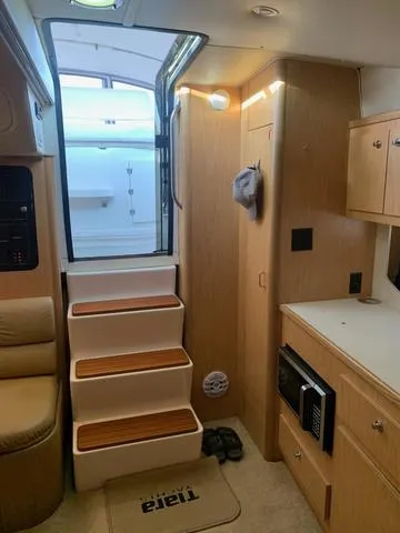 Slide: The Image of 1999 Tiara Yachts 3500 Express interior with stairs, kitchenette, and seating area. - 8