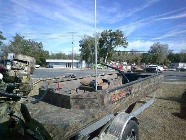 Slide: The Image of Camo-patterned Excel 1854 SWV4T boat on trailer, parked outdoors, under clear blue sky. - 7