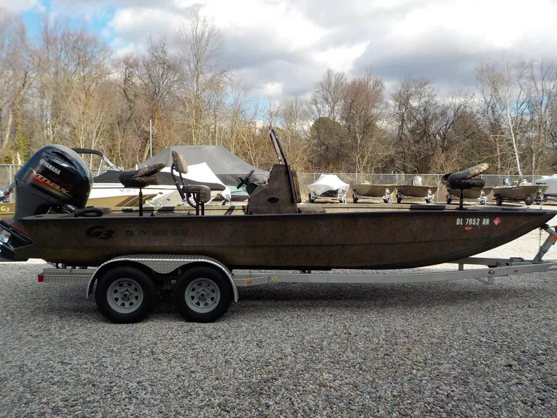 Slide: The Image of 2022 G3 Bay 22 GX boat on trailer, parked outdoors with trees in background. - 19