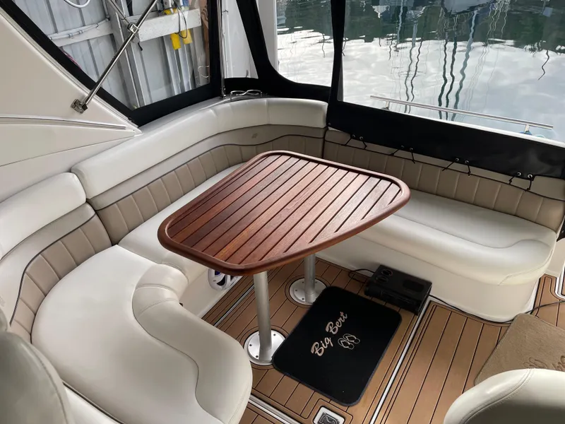 Slide: The Image of 2006 Four Winns 350 boat interior with wooden table and cushioned seating. - 15