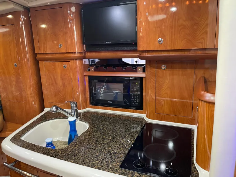 Slide: The Image of 2006 Four Winns 350 yacht kitchen with sink, stove, microwave, and TV. - 38