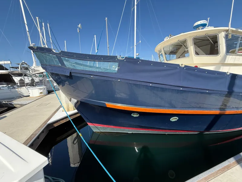 Slide: The Image of 1978 Fisher 38 Trawler docked at marina, blue hull, clear sky background. - 14