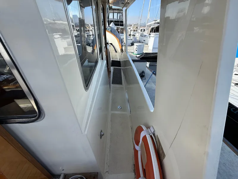 Slide: The Image of Side deck of 1978 Fisher 38 Trawler with lifebuoy and marina view. - 23