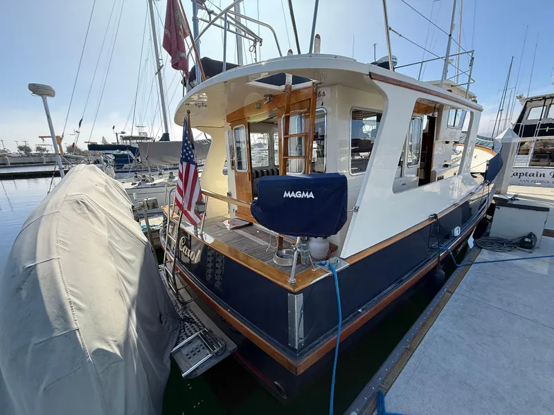 Slide: The Image of 1978 Fisher 38 Trawler docked at marina with American flag and covered equipment. - 3