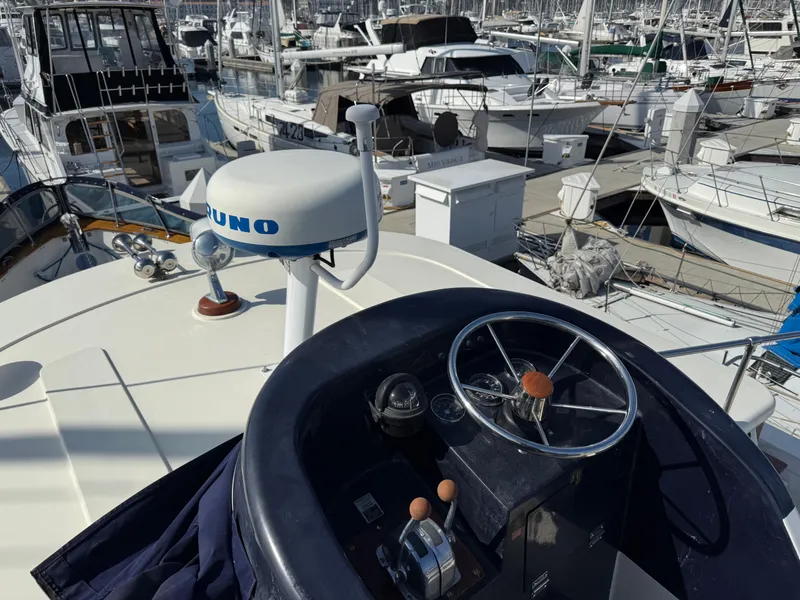 Slide: The Image of 1978 Fisher 38 Trawler helm with marina view, featuring navigation equipment and steering wheel. - 31
