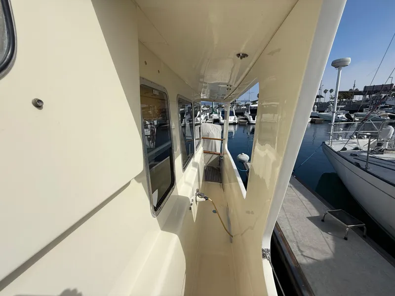 Slide: The Image of 1978 Fisher 38 Trawler side deck view at marina, showcasing windows and clean design. - 36