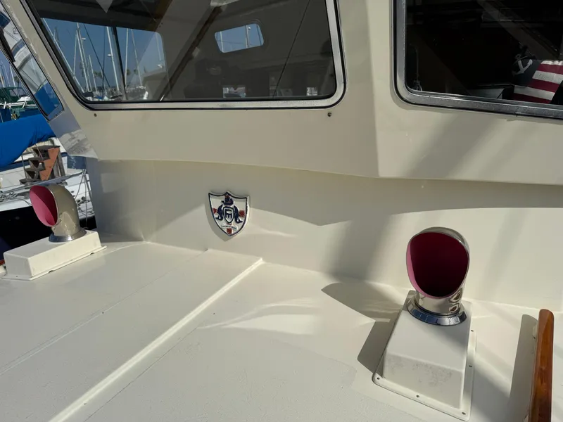 Slide: The Image of 1978 Fisher 38 Trawler deck with windows and nautical emblem in sunlight. - 42