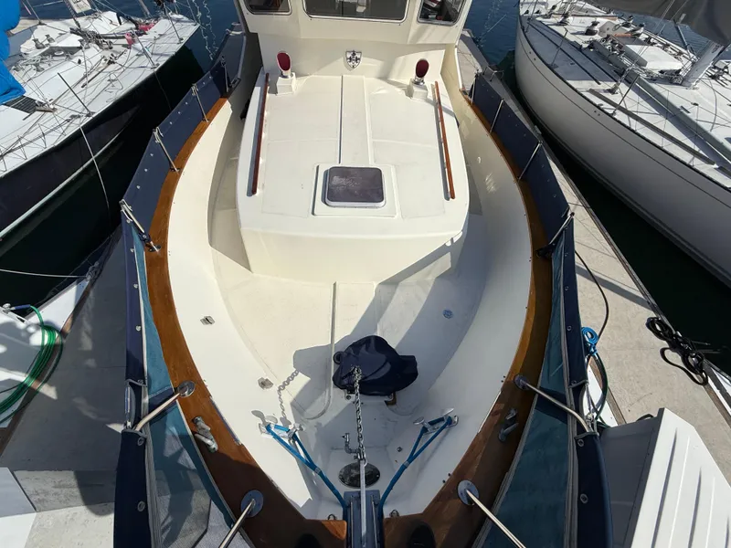 Slide: The Image of 1978 Fisher 38 Trawler boat deck with wooden railings and hatch, docked at marina. - 47