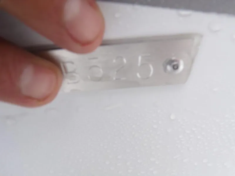 Slide: The Image of Close-up of a hand holding a metal plate with embossed numbers, Xpress SW20B 2025. - 21