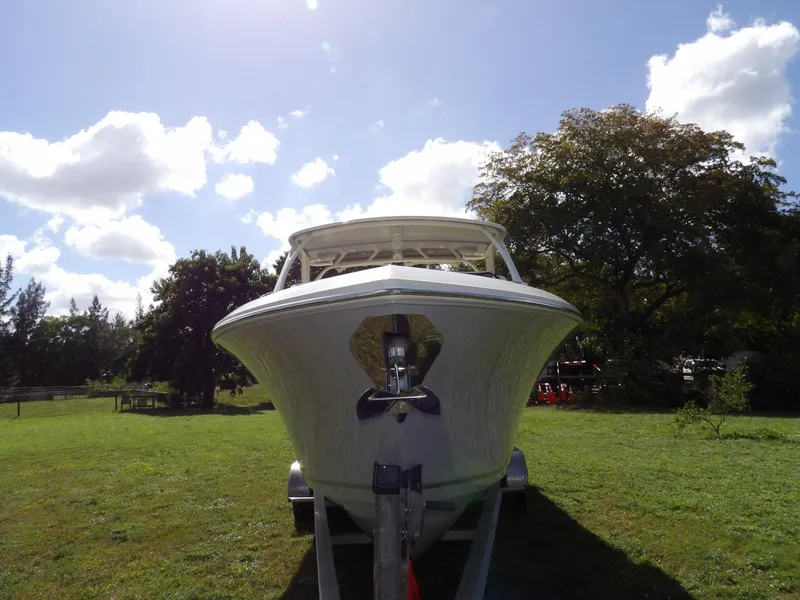 Slide: The Image of 2020 Sailfish 275 DC boat on trailer, parked on grassy area under blue sky. - 2