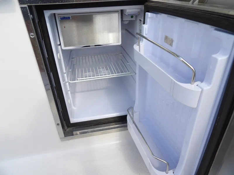 Slide: The Image of Open refrigerator inside 2020 Sailfish 275 DC boat, showing empty shelves and door storage. - 28