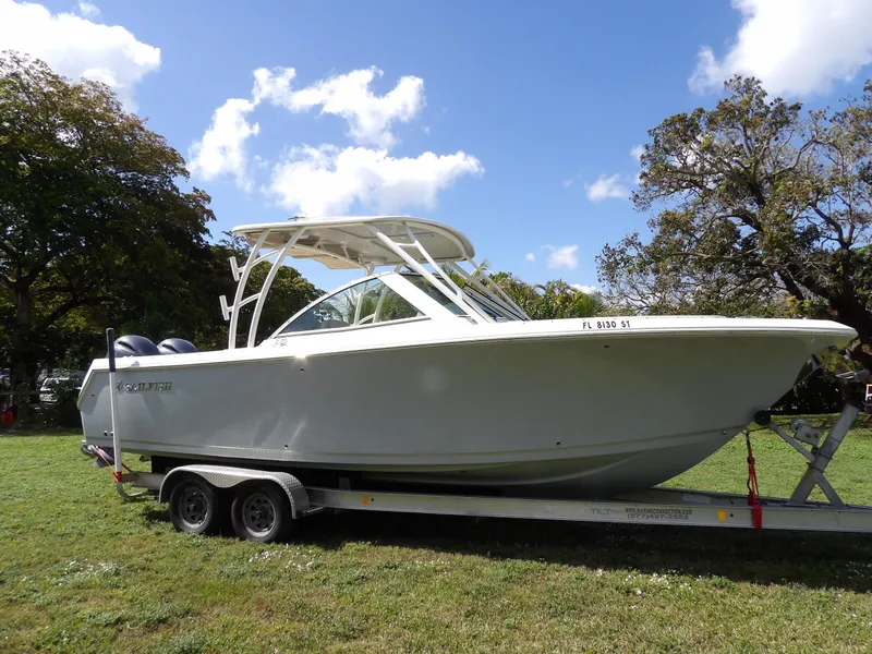 Slide: The Image of 2020 Sailfish 275 DC boat on trailer, parked on grass under a blue sky. - 4