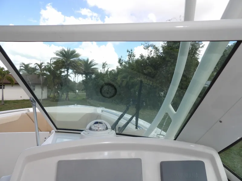 Slide: The Image of 2020 Sailfish 275 DC boat interior with windshield and compass, surrounded by palm trees. - 43