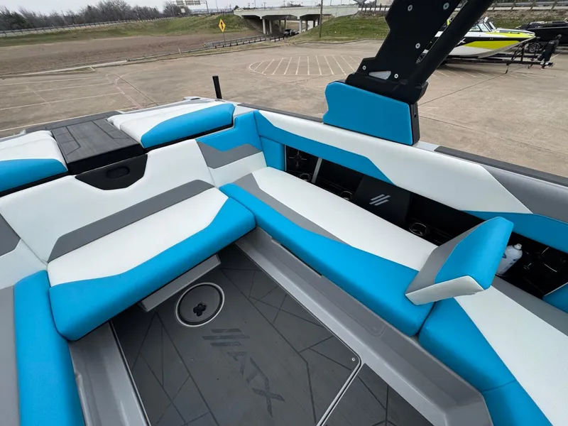 Slide: The Image of 2024 ATX Surf Boats 22 Type-S interior with blue and gray seating, docked outdoors. - 8