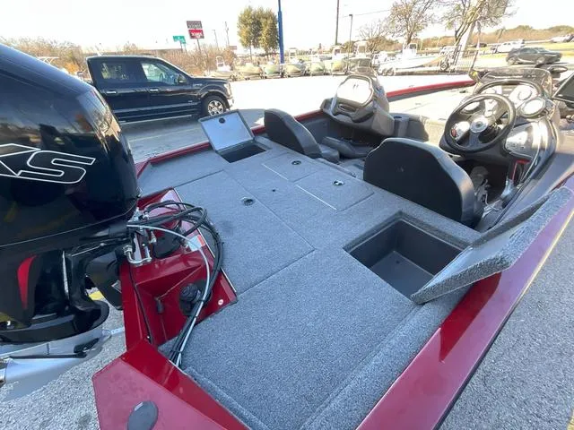 Slide: The Image of 2020 Tracker 195TXW boat interior with seating and motor, parked outdoors. - 11