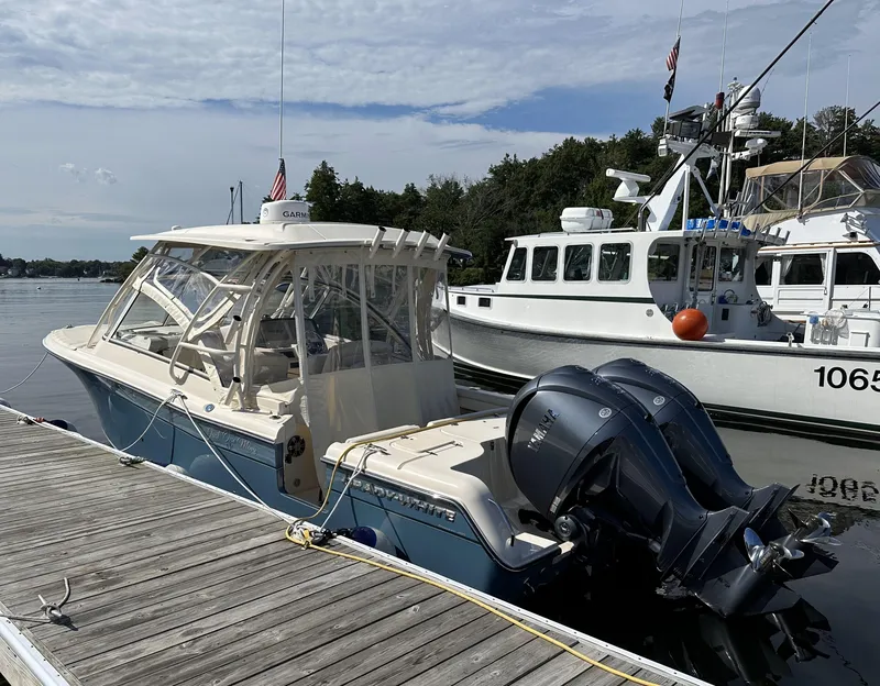 Slide: The Image of 2021 Grady-White Freedom 285 boat docked, featuring dual outboard engines and a covered cabin. - 2