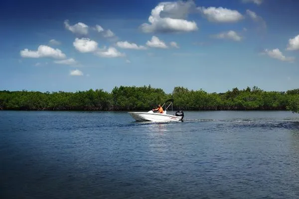 Slide: The Image of 2024 Boston Whaler 130 SUPERSPORT cruising on a serene lake under a blue sky. - 9