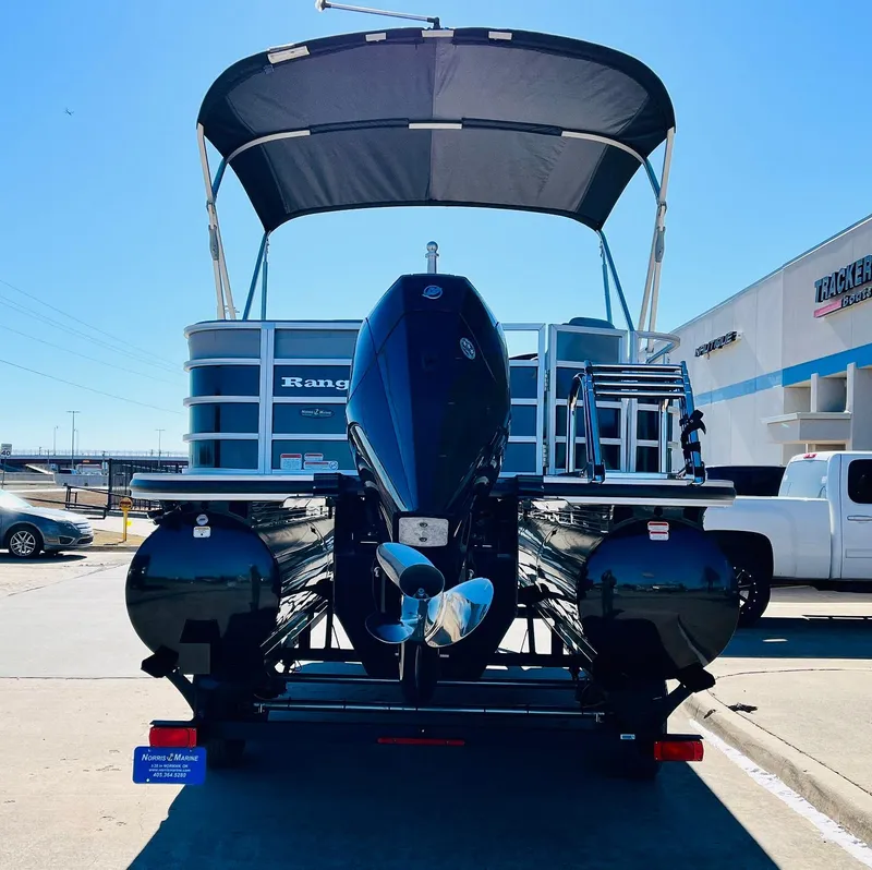 Slide: The Image of 2025 Ranger Reata 223C pontoon boat with canopy, rear view, parked outdoors. - 6