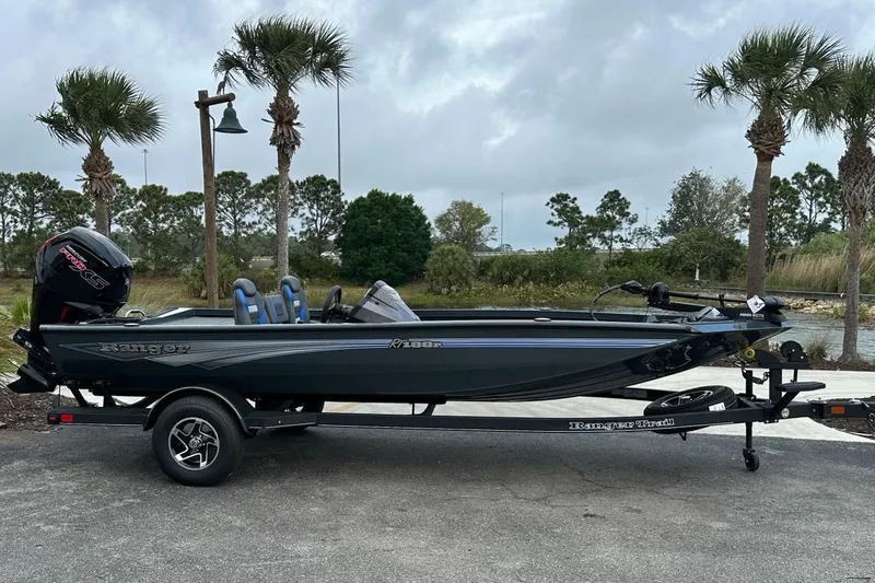 Slide: The Image of 2025 Ranger RT188P boat on trailer, parked near palm trees under cloudy sky. - 1