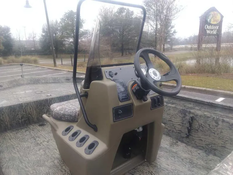 Slide: The Image of 2025 Tracker Grizzly 1860 CC boat console with steering wheel, parked outdoors. - 10