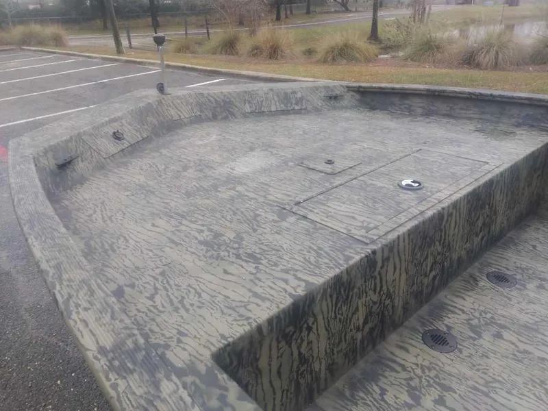 Slide: The Image of 2025 Tracker Grizzly 1860 CC boat with camouflage design in a parking lot. - 8