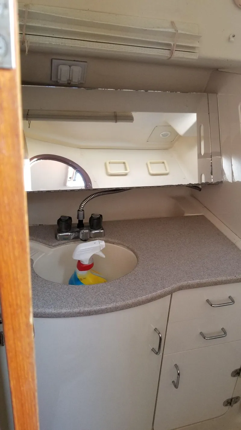 Slide: The Image of 1999 Hunter 340 yacht bathroom with sink, mirror, and storage cabinets. - 10