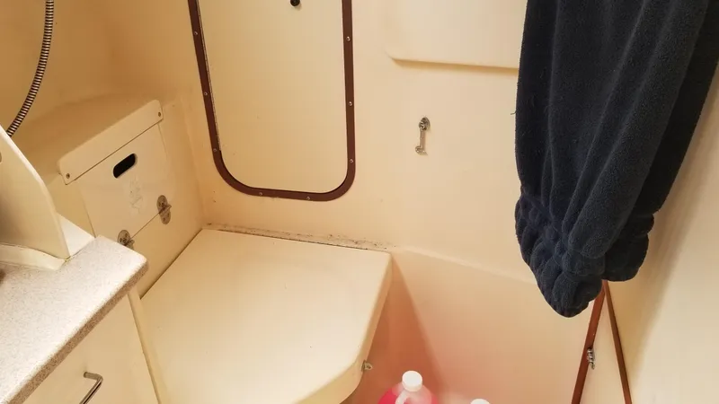 Slide: The Image of 1999 Hunter 340 boat bathroom with storage, towel, and cleaning supplies. - 13