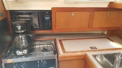 Slide: The Image of 1999 Hunter 340 yacht kitchen with stove, coffee maker, microwave, and wooden cabinets. - 20