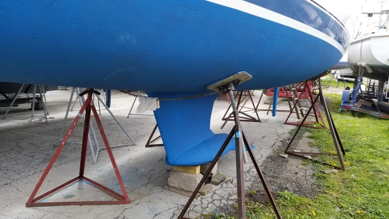 Slide: The Image of 1999 Hunter 340 sailboat on stands, blue hull, keel visible, outdoor storage. - 5