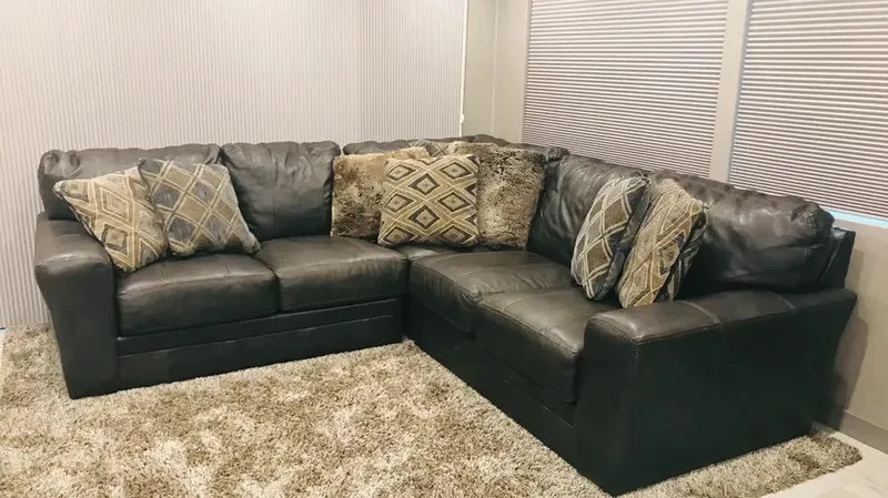 Slide: The Image of Luxurious black leather sectional sofa with patterned cushions on a plush beige carpet. - 10