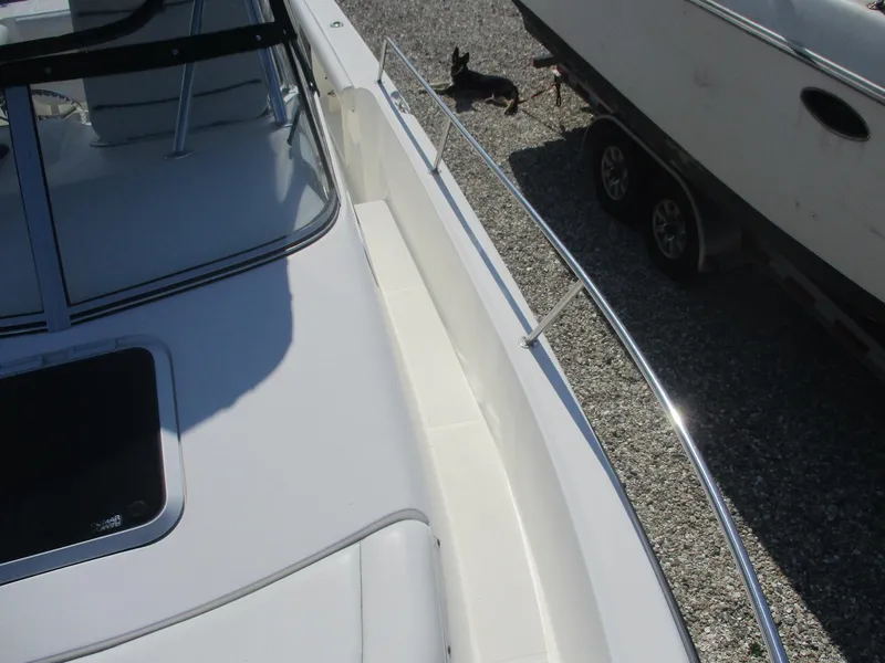 Slide: The Image of 2001 Shamrock 246 Walkaround boat with sleek deck and railing, parked on gravel. - 28
