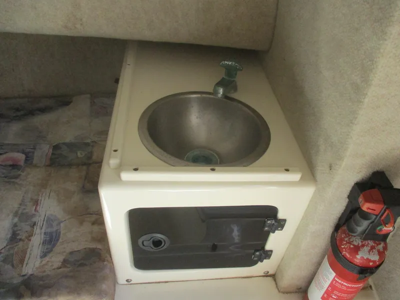 Slide: The Image of Compact sink area in 2001 Shamrock 246 Walkaround boat interior with fire extinguisher. - 34