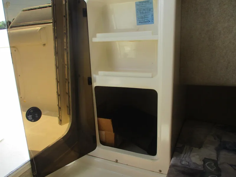 Slide: The Image of Open storage compartment inside 2001 Shamrock 246 Walkaround boat, featuring shelves and a dark interior. - 36